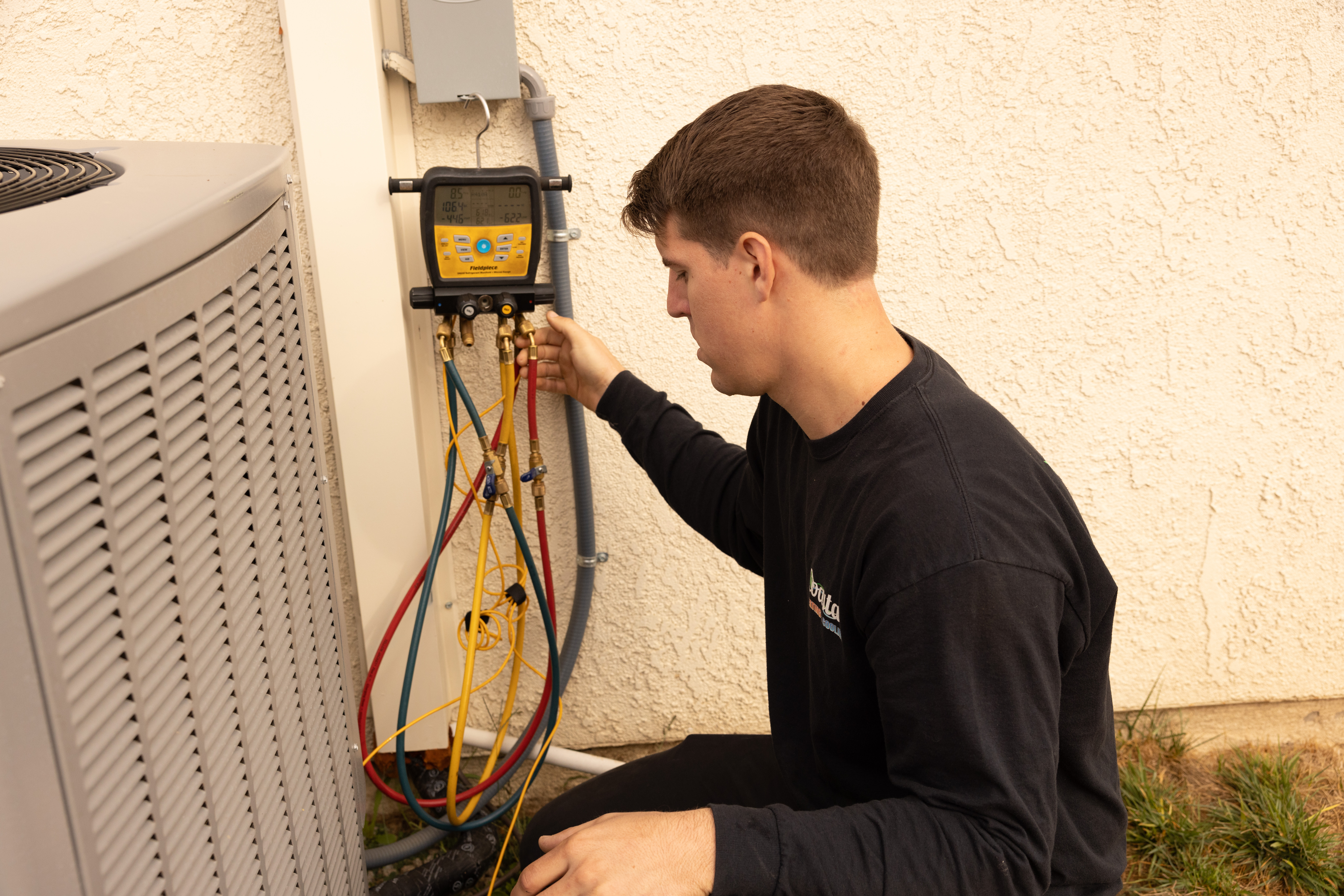 A Coastal HVAC technician servicing an outdoor AC unit.